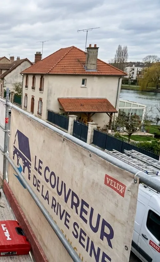 Bâche Le Couvreur de la Rive Seine sur un échafaudage au-dessus d'une maison en bord de Seine à Melun